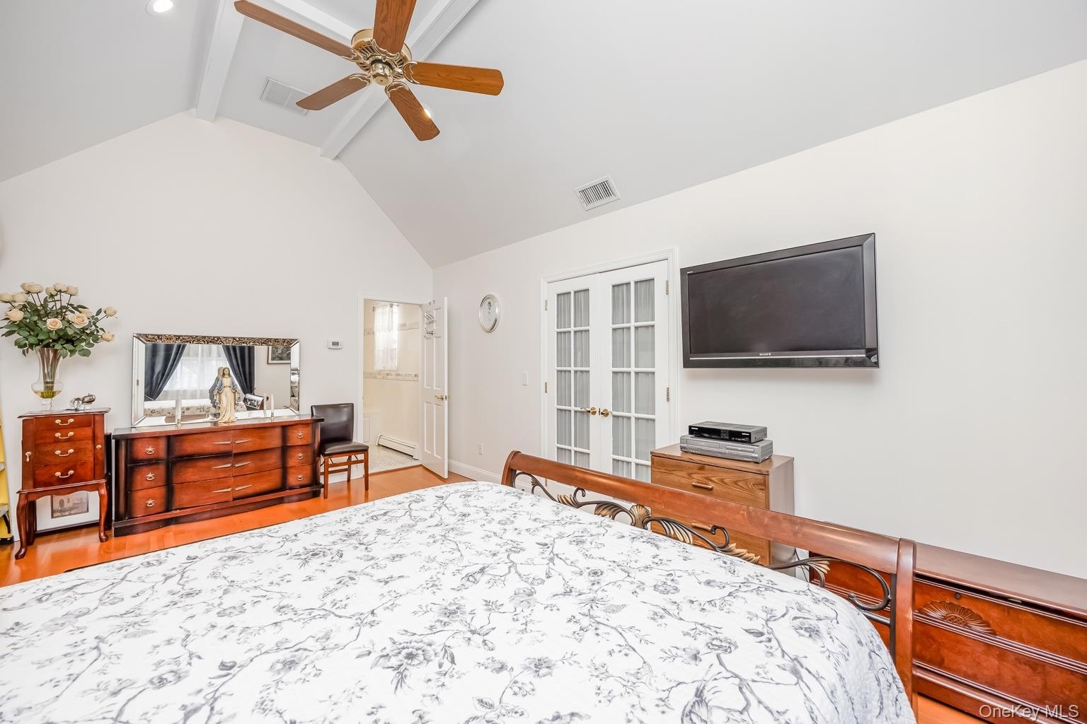Vaulted ceiling with exposed beams, wood-finish flooring, recessed lighting, and French doors