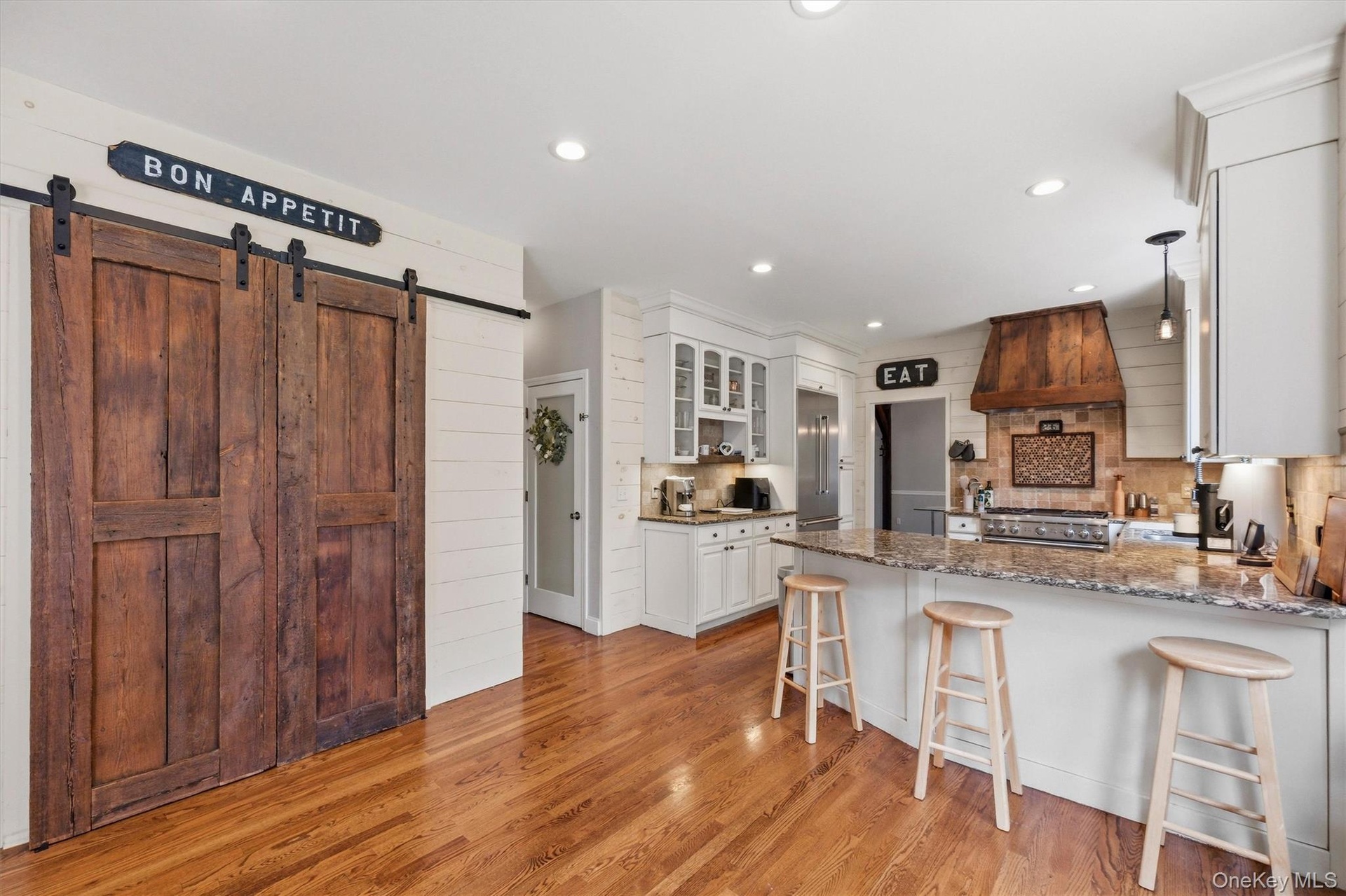 A custom walk-in pantry, beautifully appointed with reclaimed wood doors, provides additional storage while adding warmth and character to the space.