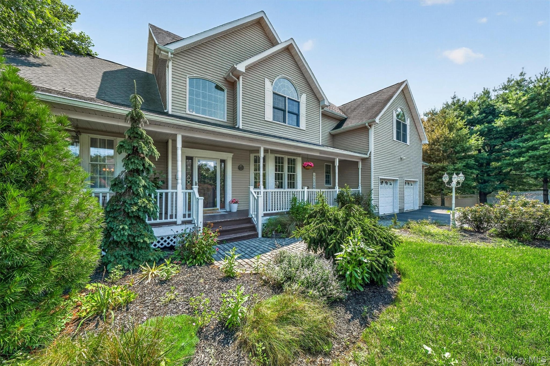 The property is beautifully landscaped with mature trees, lush greenery, and an array of flowering plants.