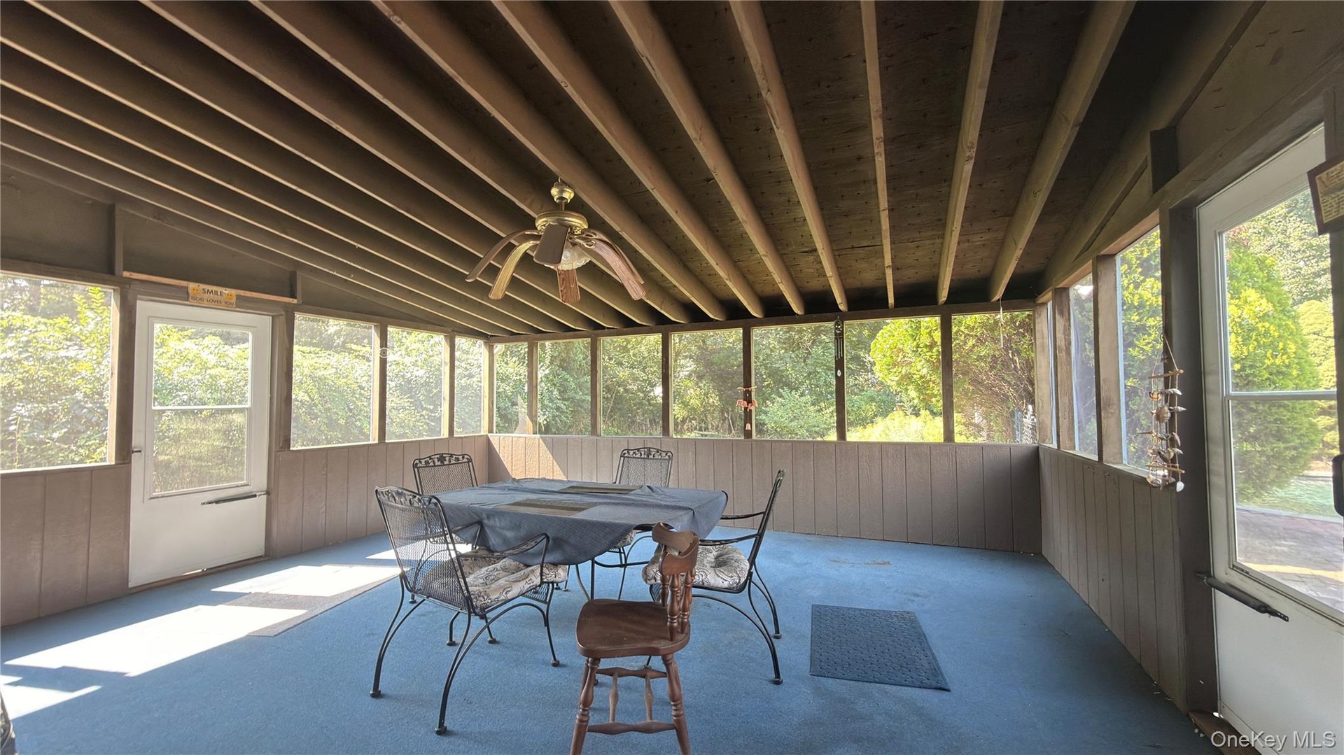 Screened porch featuring a slatted wood ceiling, ceiling fan, and extensive natural light