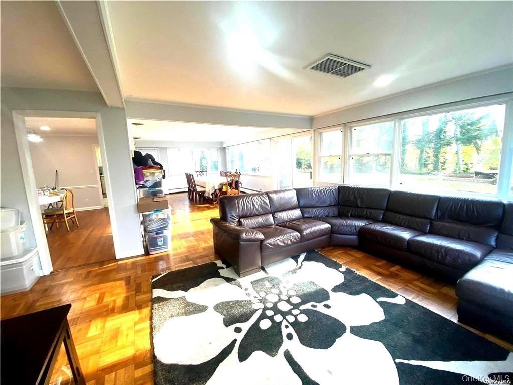 Expansive living area featuring wood-finish flooring, white trim, and a large window wall