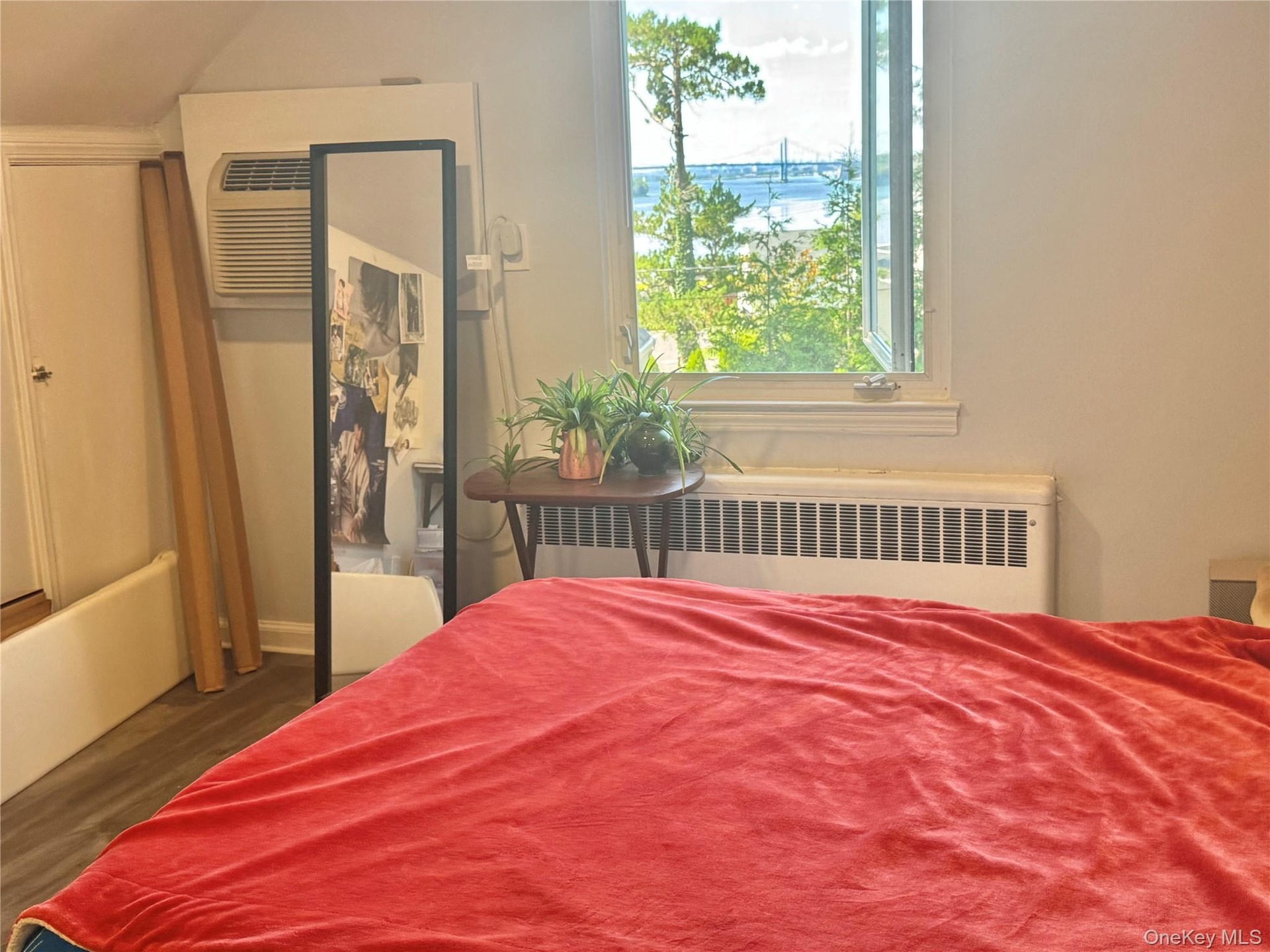 Window offering a scenic water backdrop, window-mounted air conditioning unit, and baseboard heating
