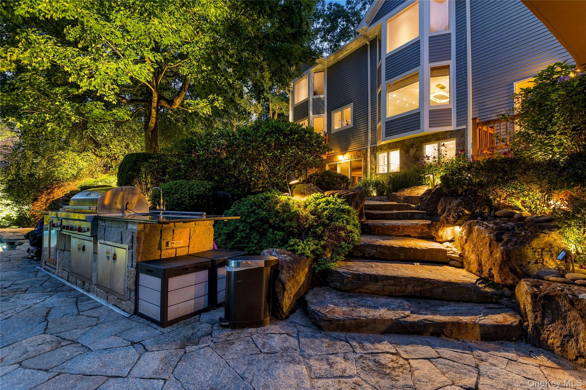 Close-up of the outdoor Kitchen at twilight, with natural stone steps from lower patio to upper patio