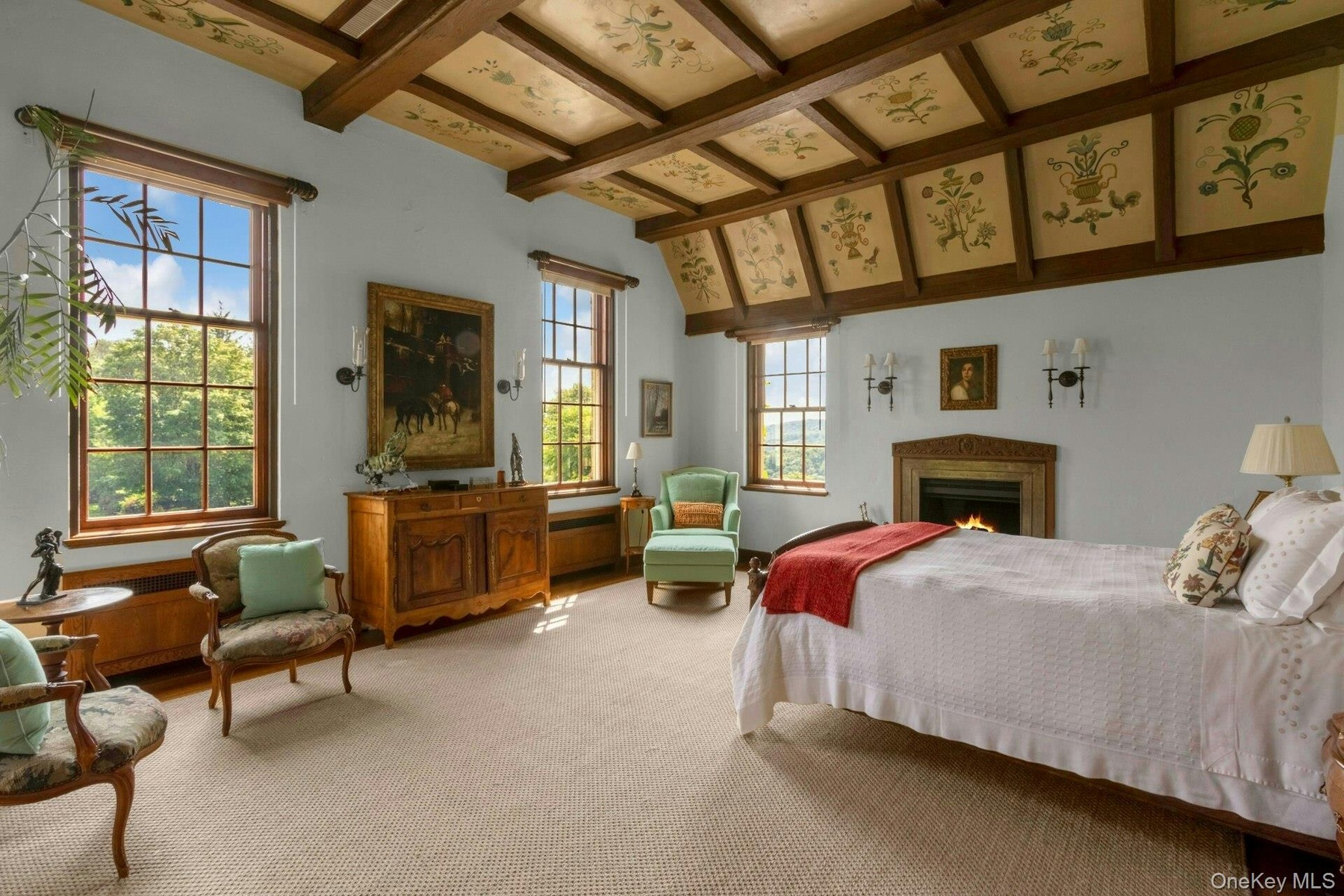 Carpeted bedroom with beamed ceiling and a warm lit fireplace
