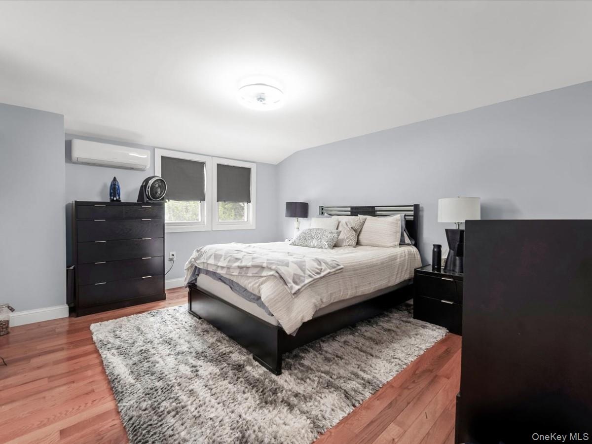 Primary Bedroom: Spacious and bright with hardwood floors, recessed lighting, multiple windows, and a split A/C unit.