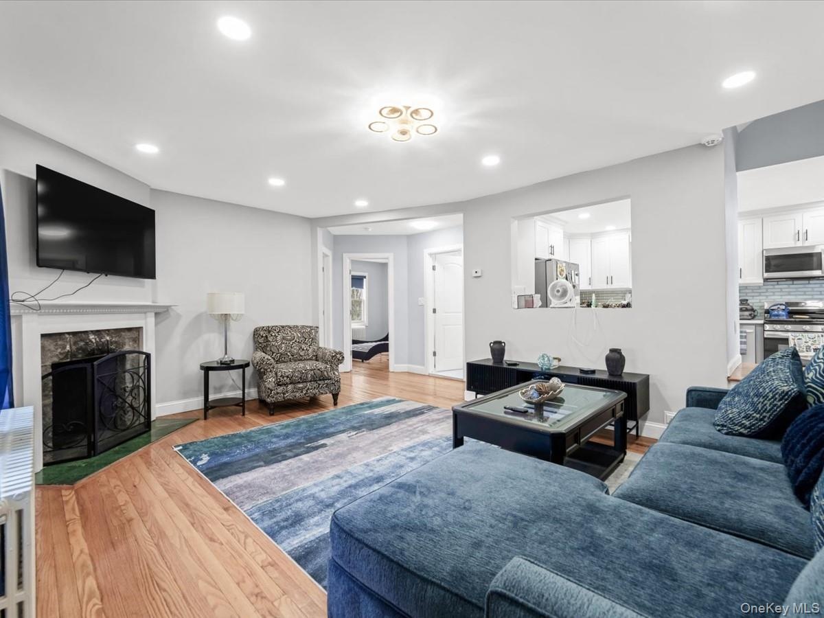 Hardwood flooring, recessed lighting, and a fireplace with a decorative screen