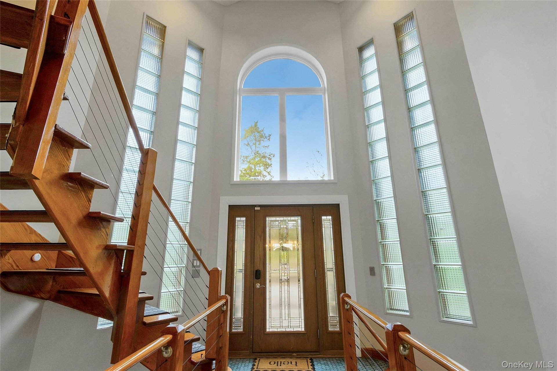 Two-story foyer with an arched transom window, two-panel wood entry door, and vertical glass block windows