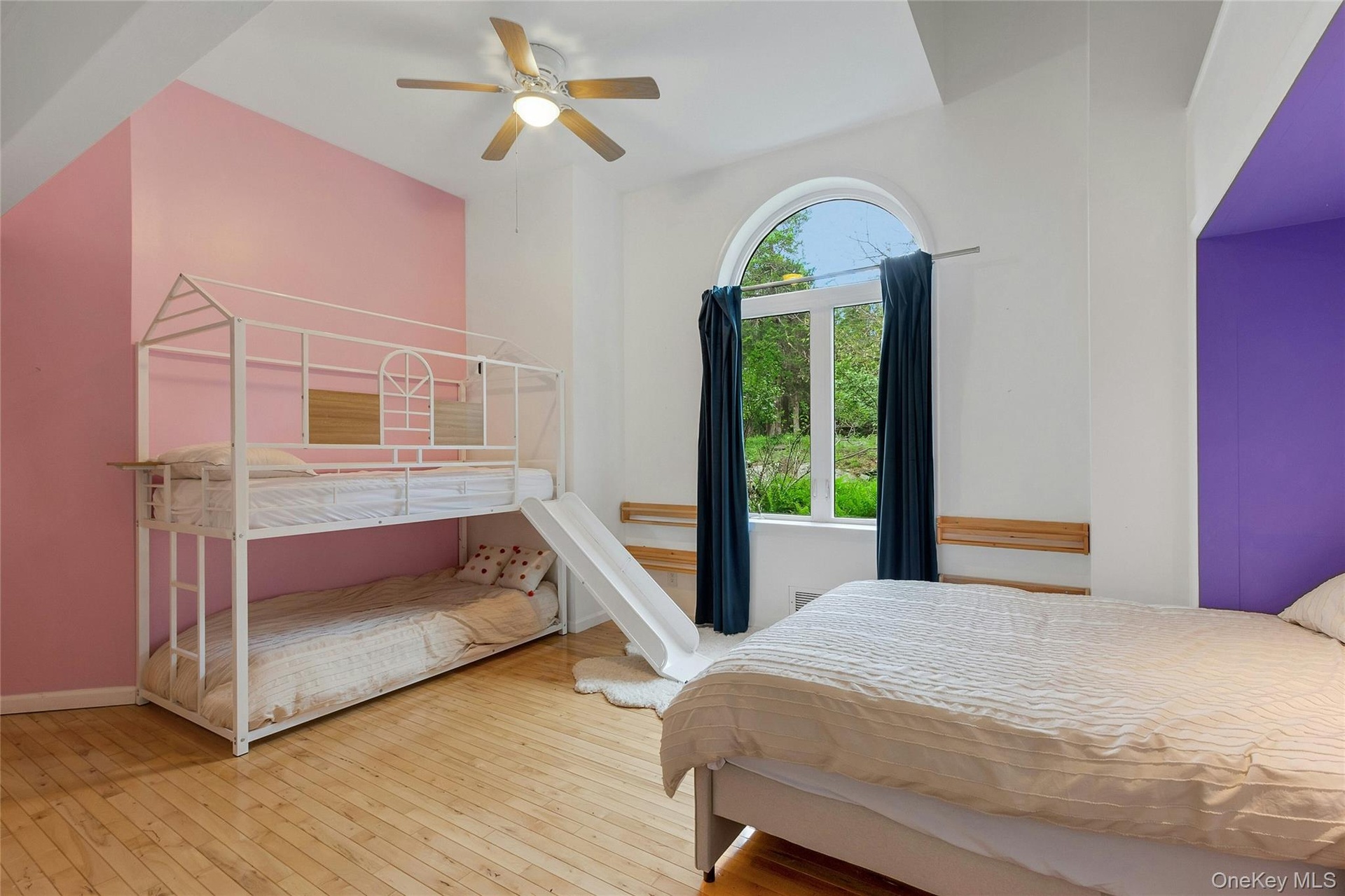 Arched window, wood-finish flooring, ceiling fan, and built-in alcove