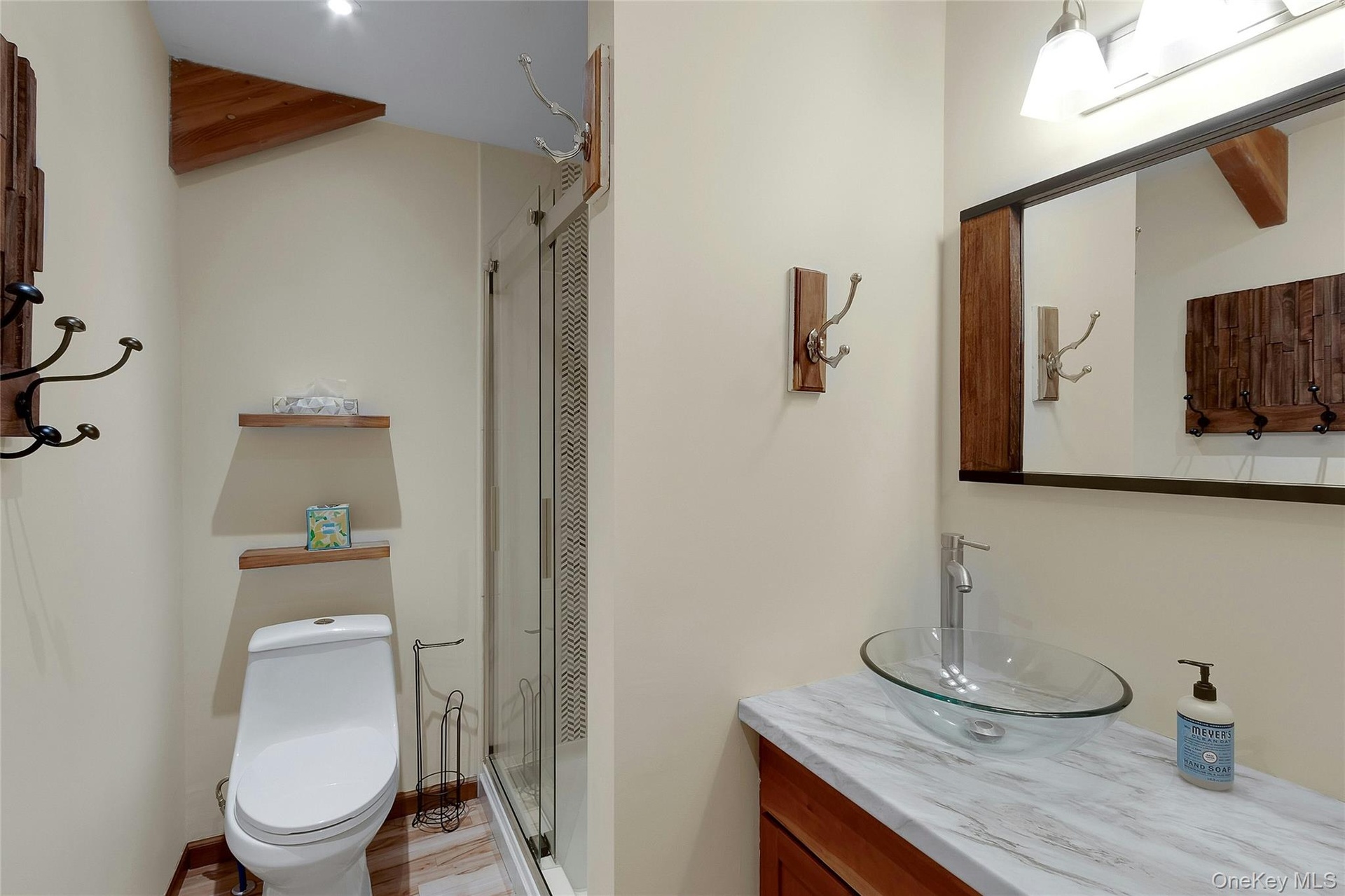 Bathroom featuring a vessel sink, a shower with a clear glass enclosure, and a vanity with a light-toned countertop