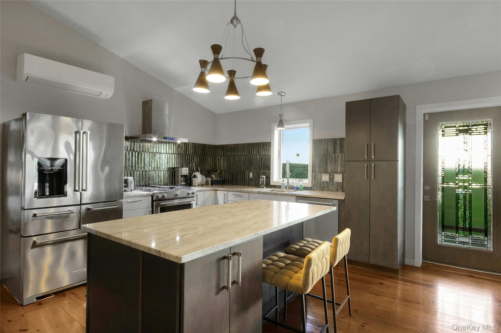 Kitchen featuring a vaulted ceiling, wood-finish flooring, stainless steel appliances, a center island with countertop, and a decorative glass door