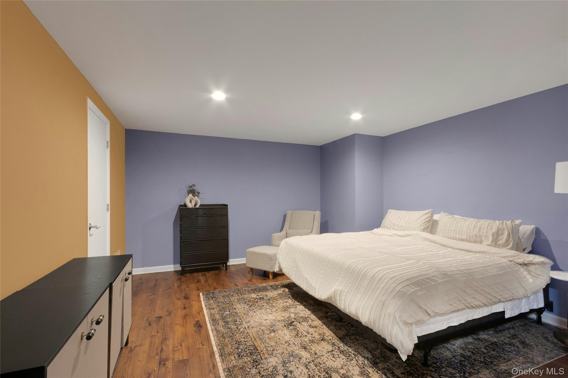 Recessed lighting, wood-finish flooring, and a white door with contemporary hardware