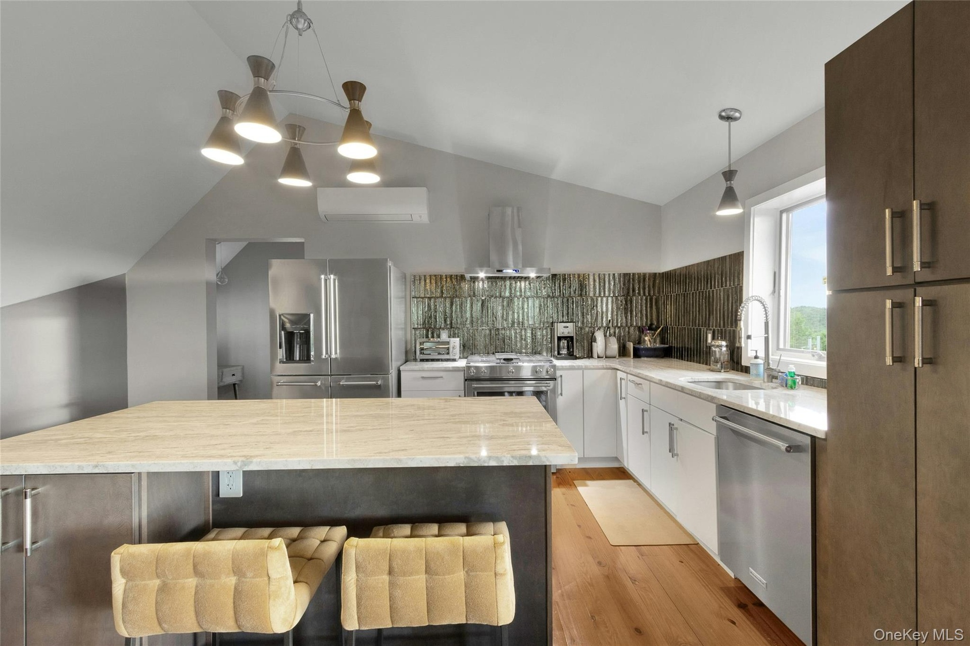 Spacious kitchen featuring an angled ceiling, large center island with stone countertop, stainless steel appliances, and a tiled backsplash