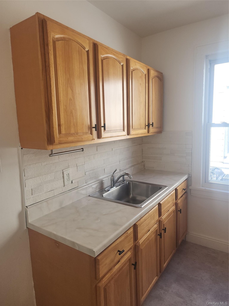 Light wood cabinetry with arch panel doors and dark hardware