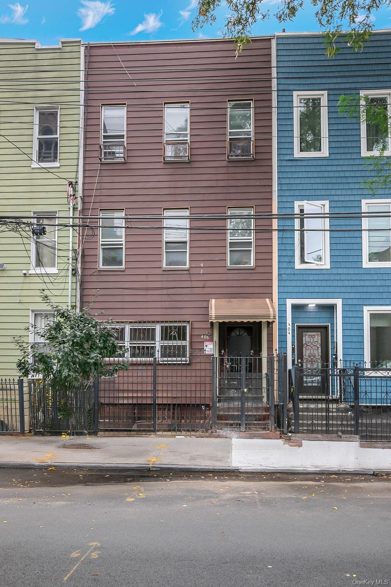 Three-story facade with horizontal siding, multiple windows, and a shaded entrance