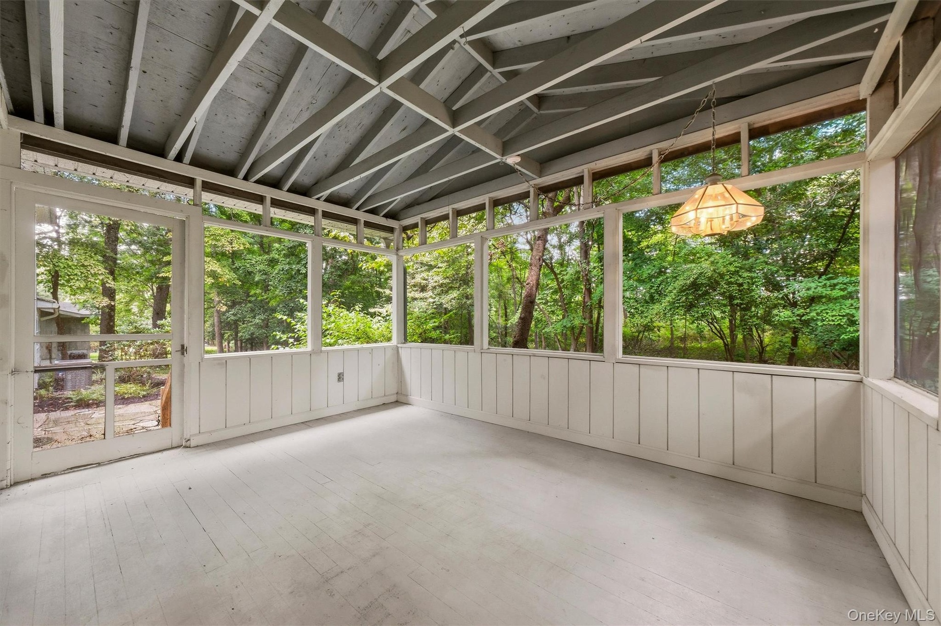 Screened porch overlooks wooded backyard