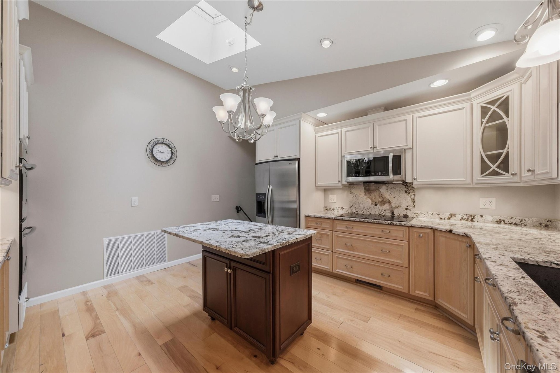 Custom kitchen with center island and snack bar, stainless appliances including double ovens, granite counters and wood floors