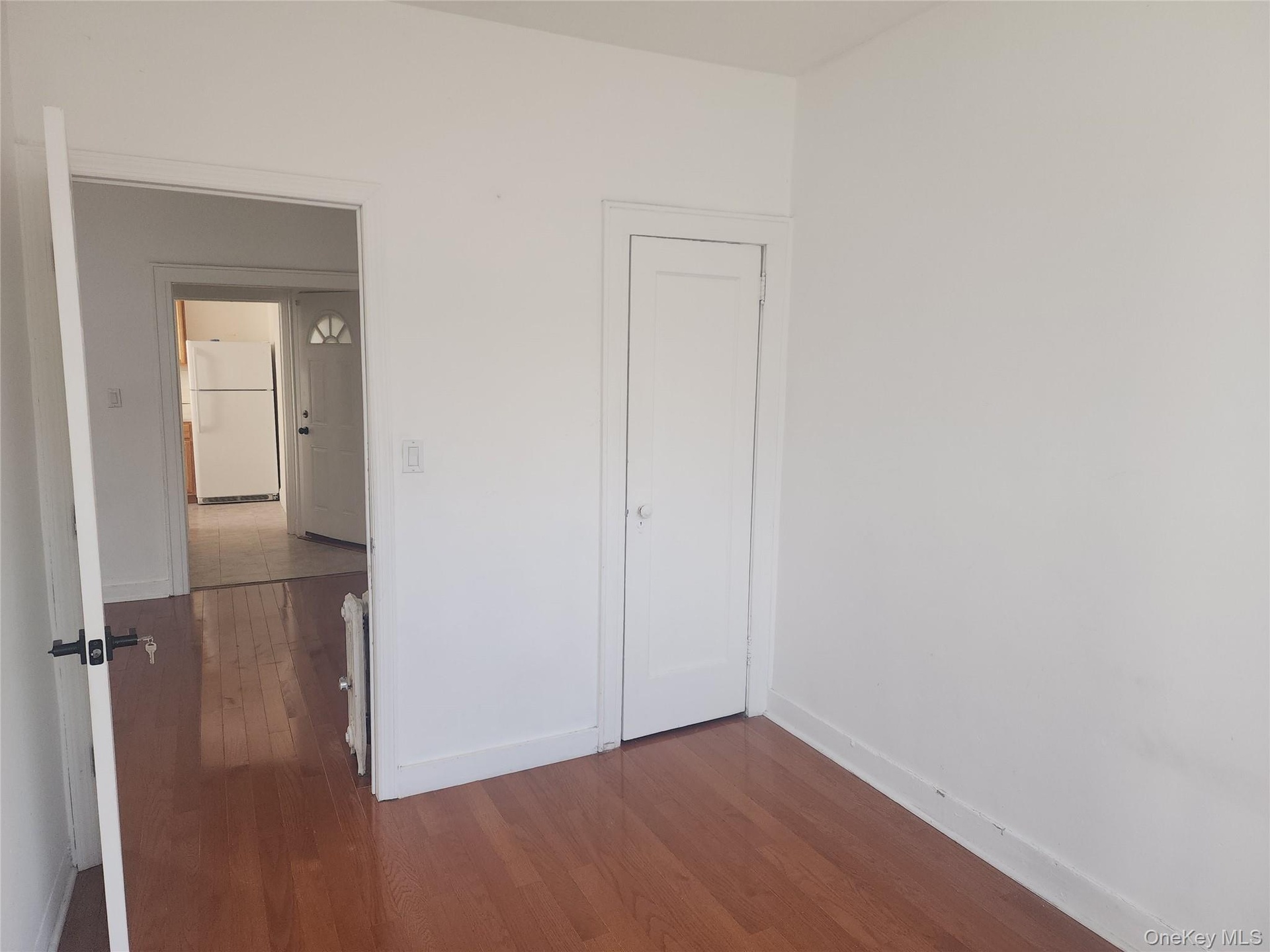 Wood-finish flooring with white base trim, white walls, and a white closet door
