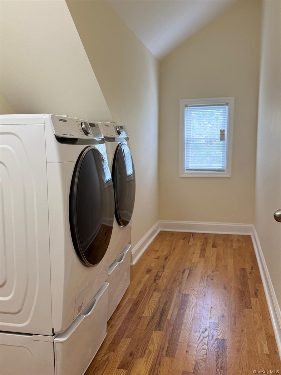 Wood-finish flooring, white trim, and a window with blinds