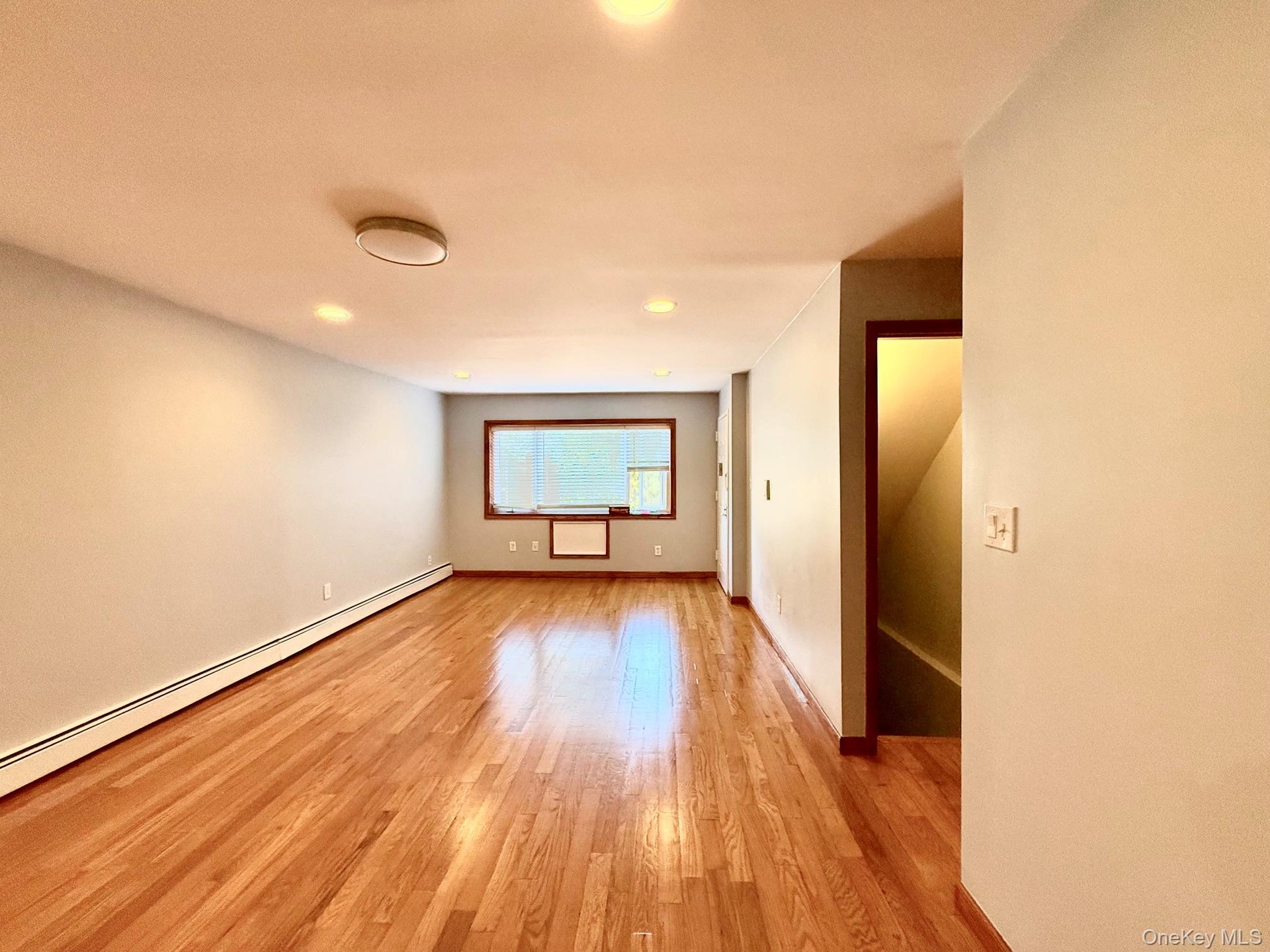 Hardwood flooring, recessed lighting, ceiling-mounted light fixture, window with wood trim, and baseboard heating