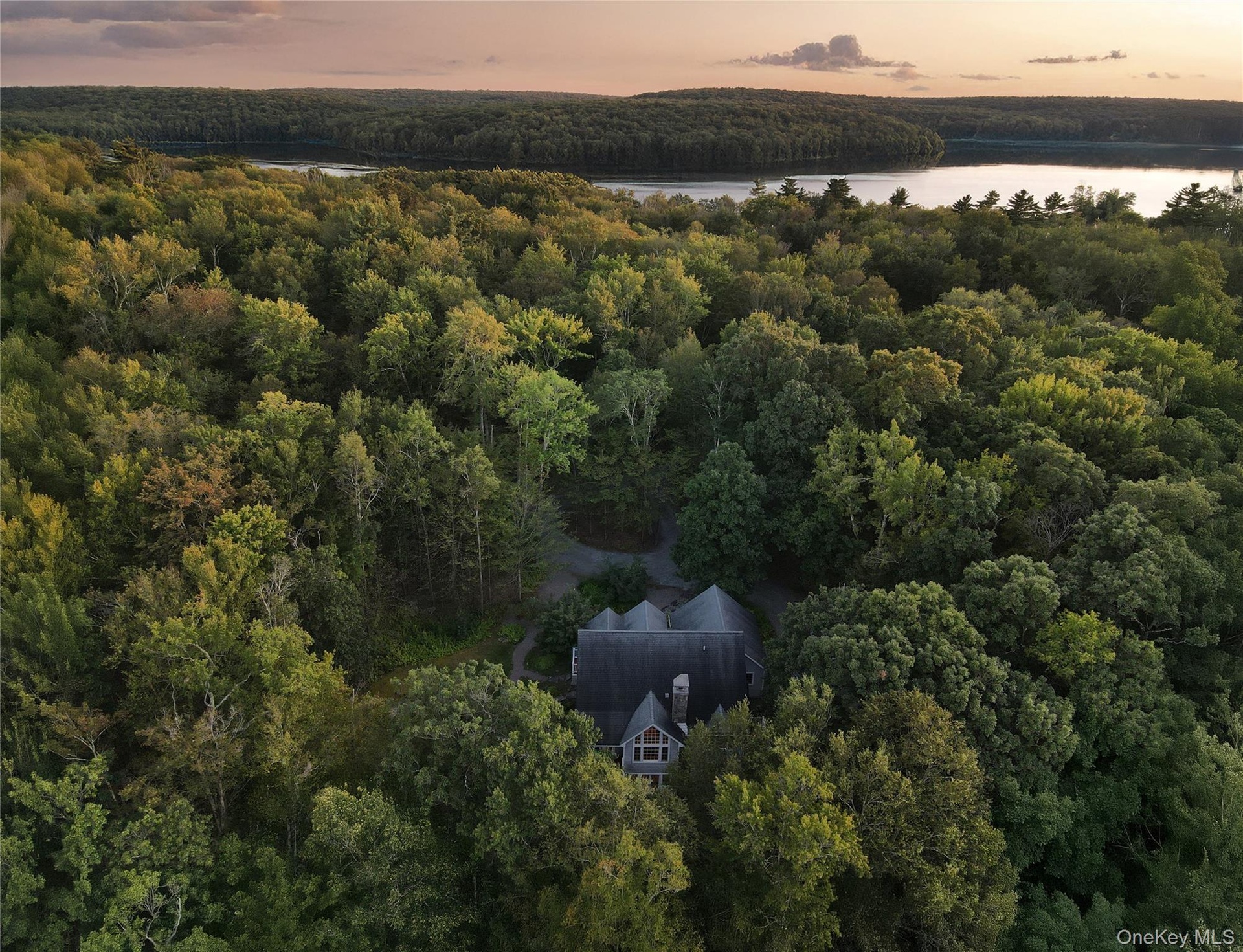 View of subject property featuring a heavily wooded area and a large body of water