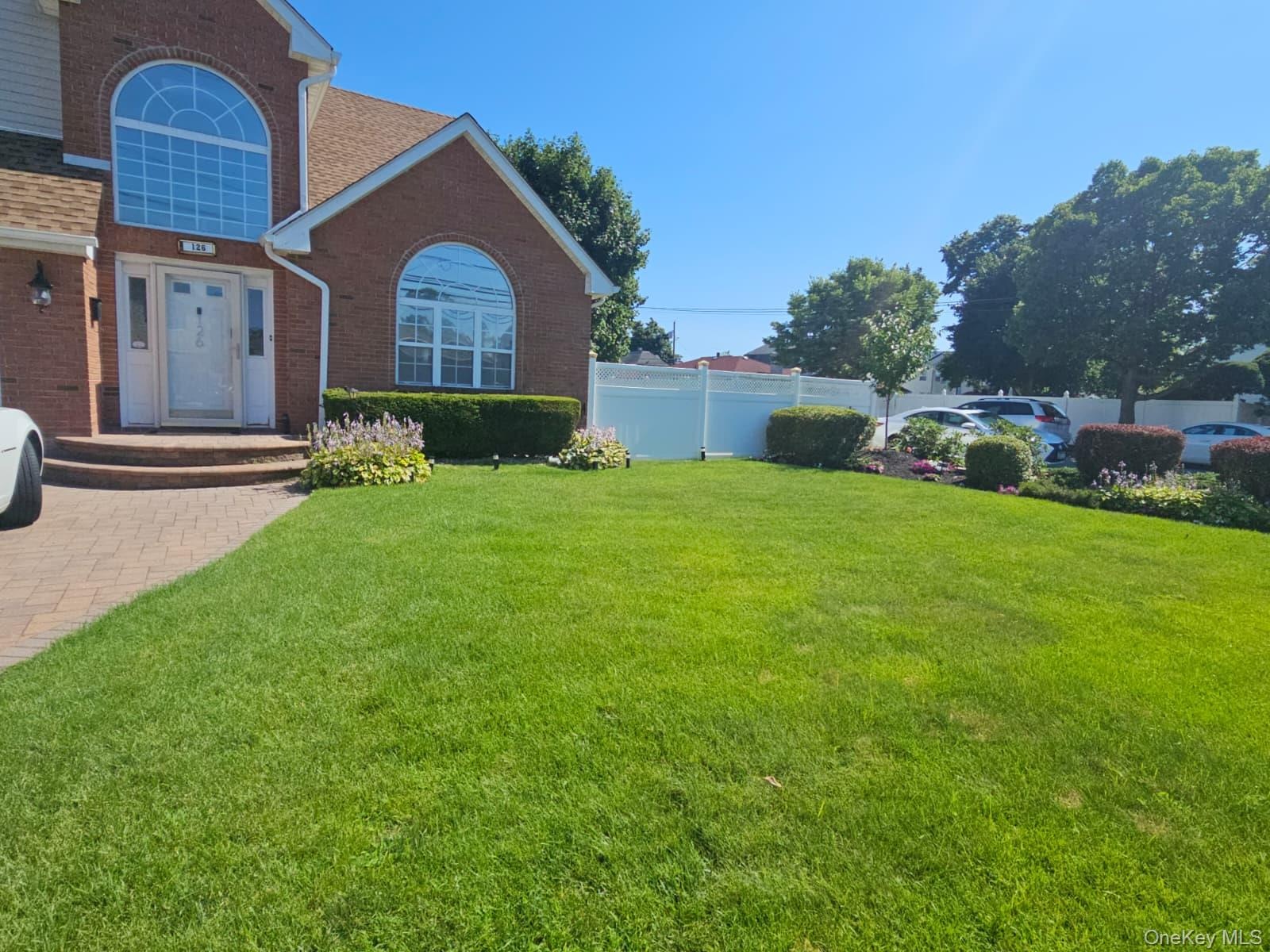 Brick exterior with a prominent arched window and a paver driveway