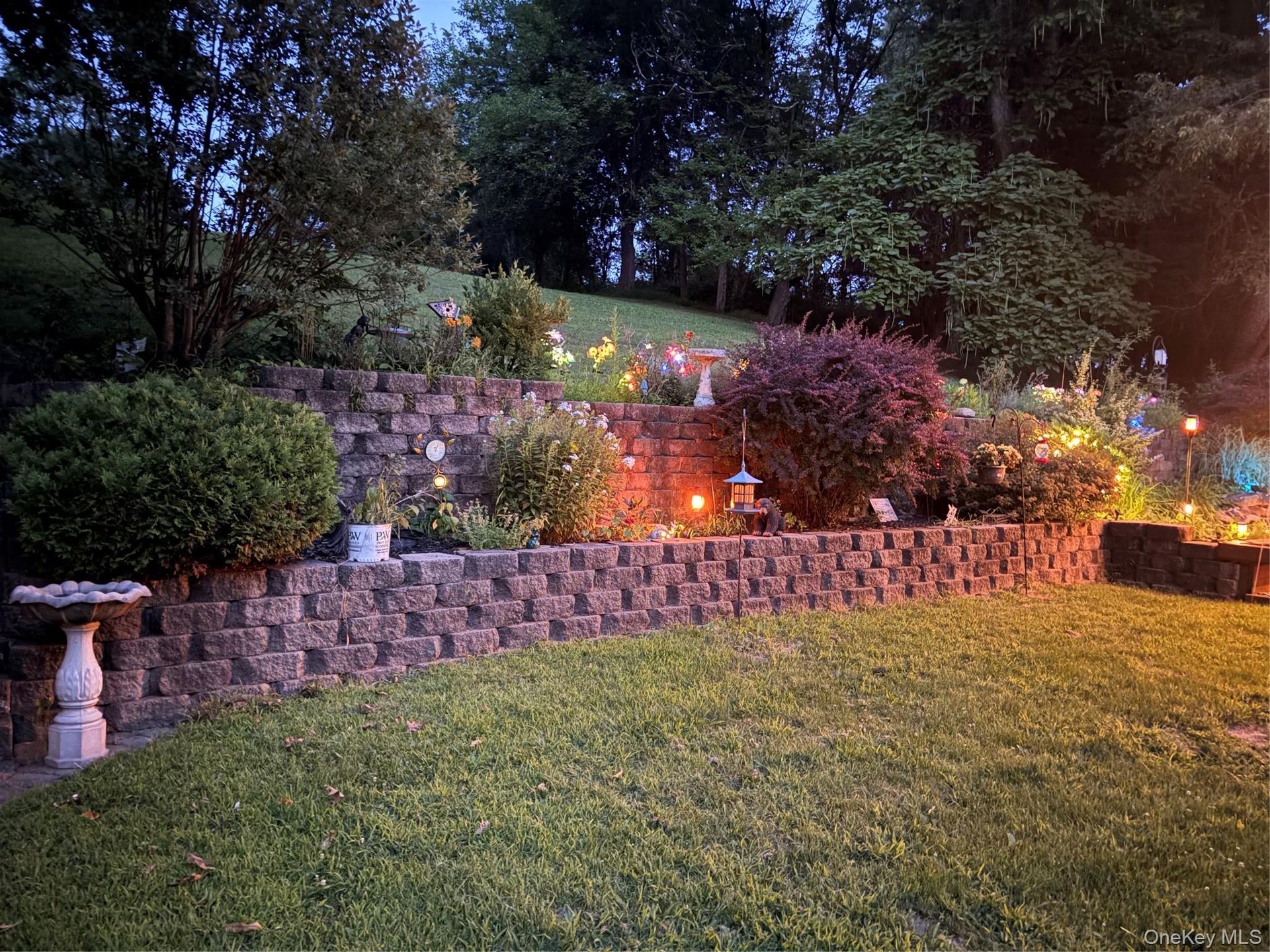 Terraced landscaping featuring retaining walls, mature shrubs, and planted beds