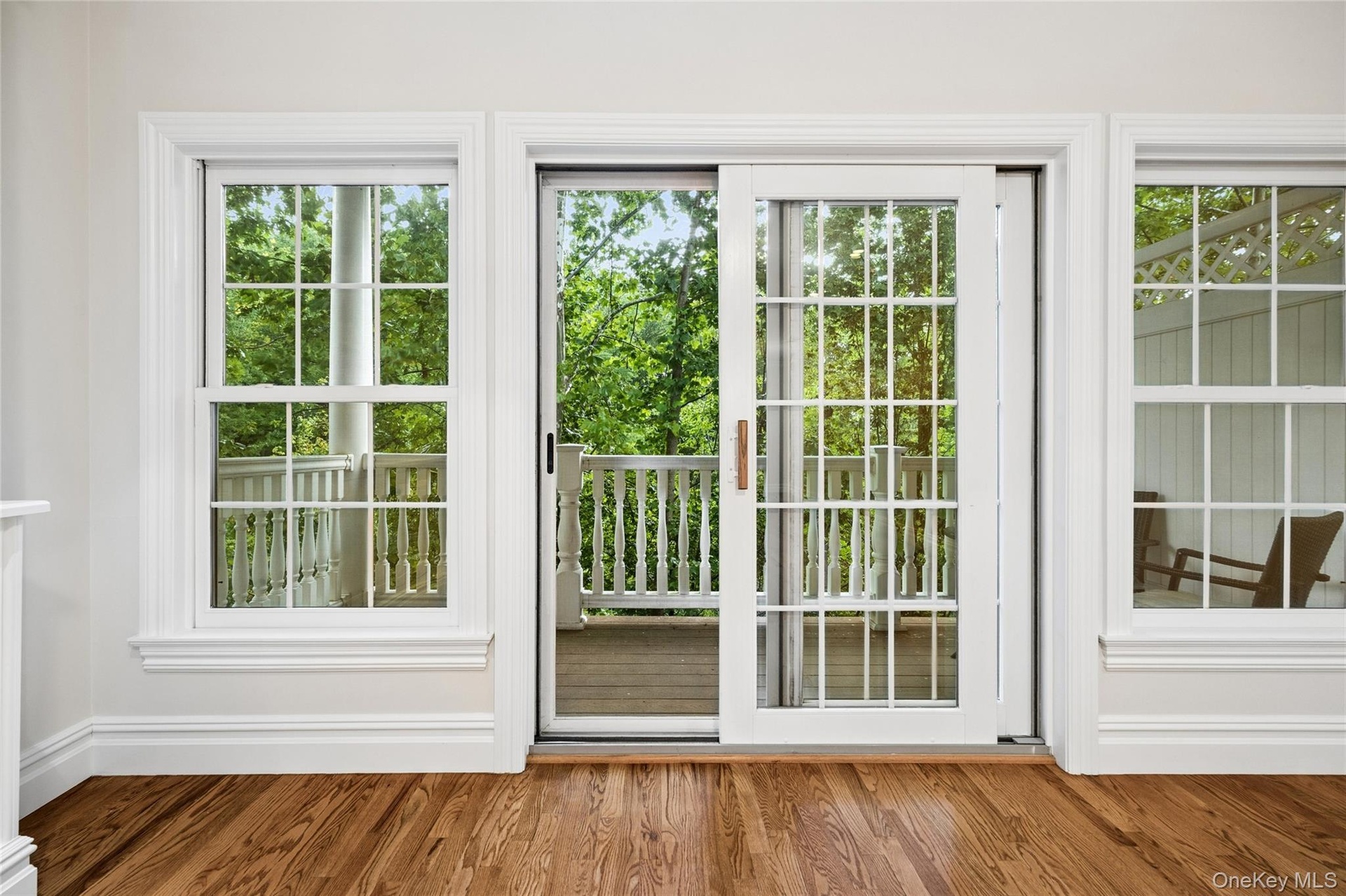 Rich wood-finish flooring, white trim, and multiple windows with muntin bars
