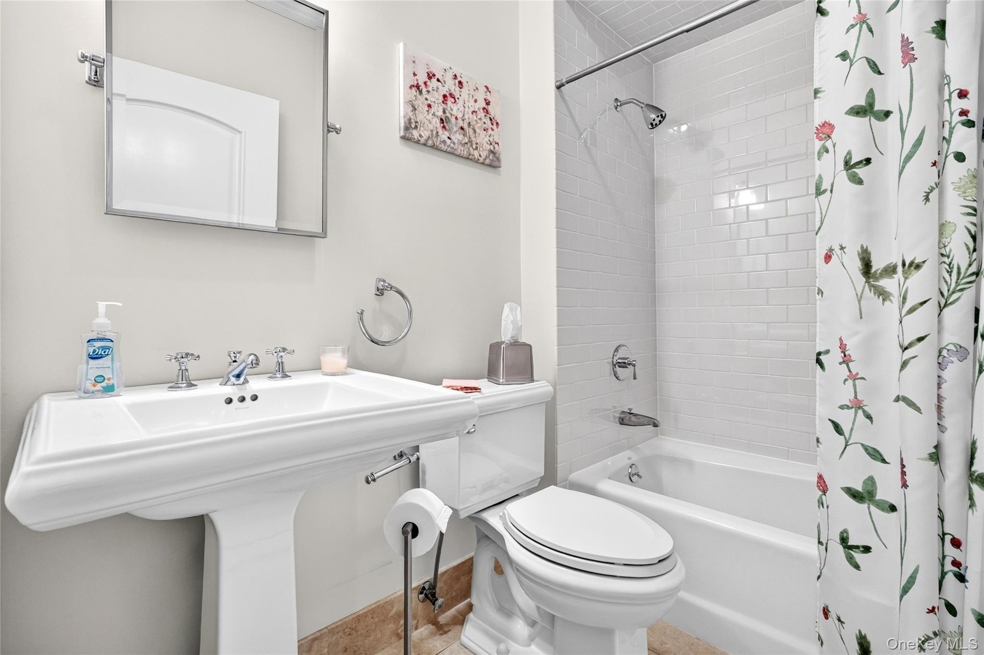 White pedestal sink with chrome fixtures, white subway tile shower surround, and a built-in bathtub