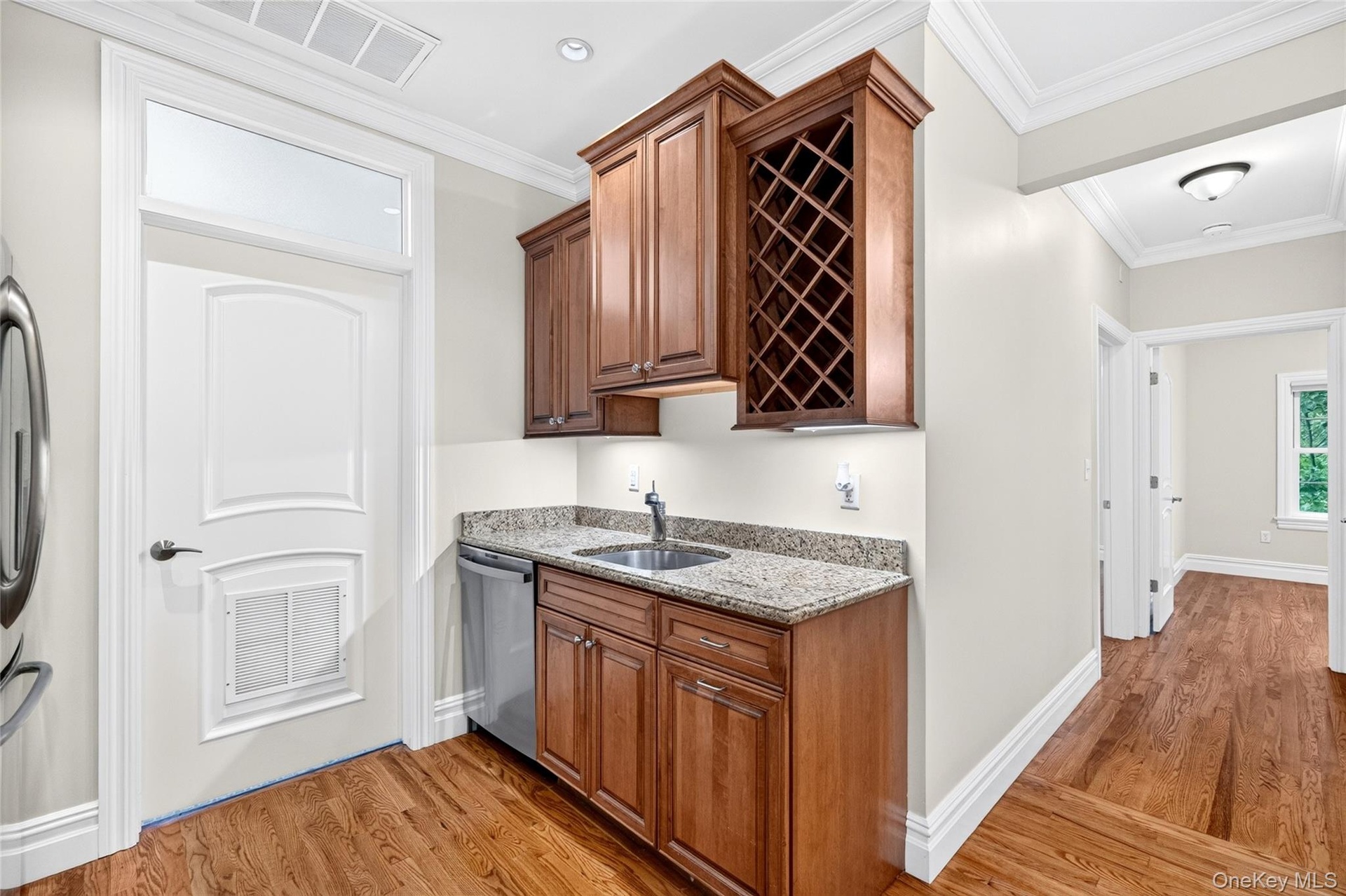 Wet bar with wood cabinetry, integrated wine rack, and granite countertop