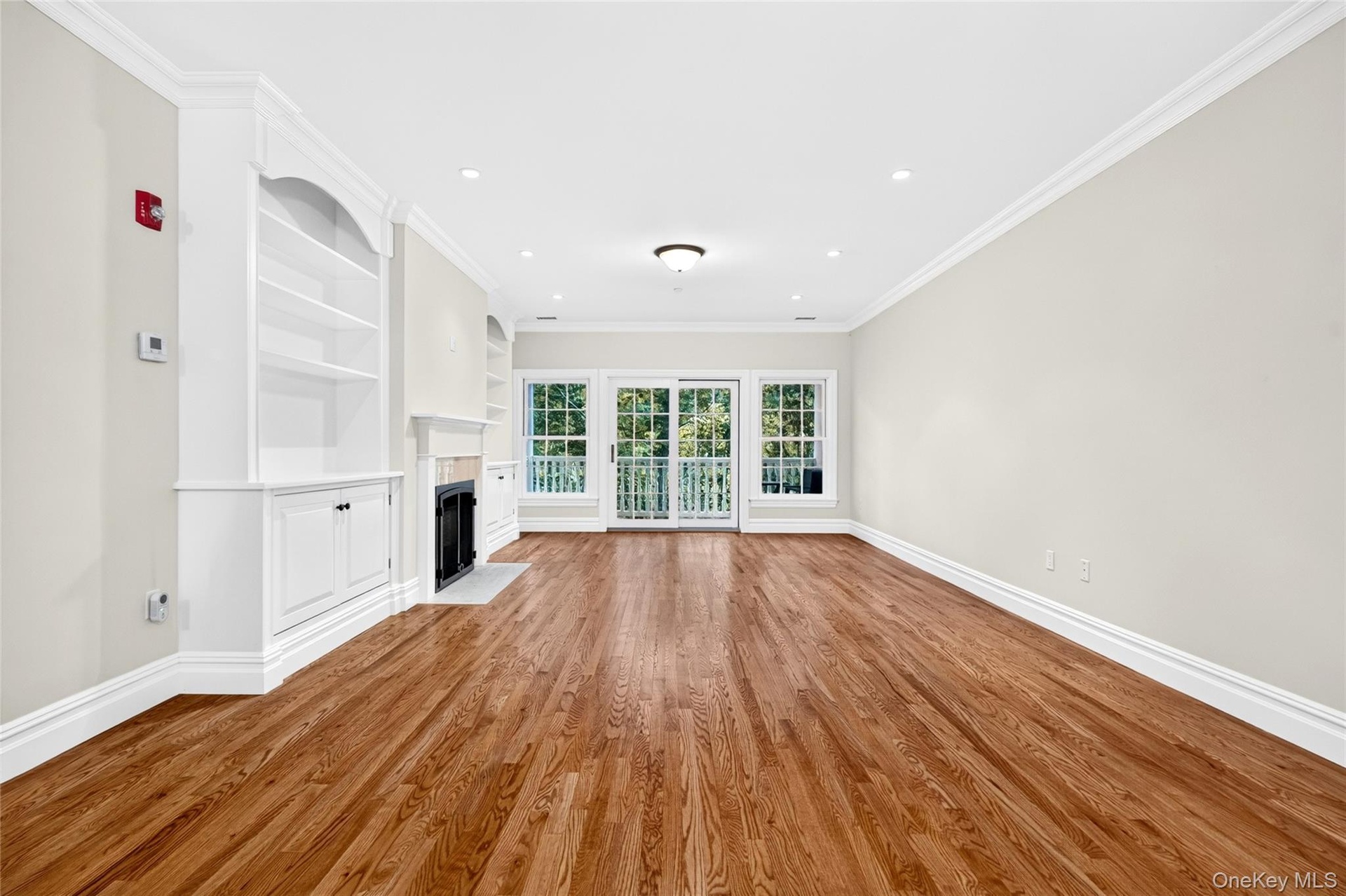 Hardwood flooring throughout, built-in shelving, fireplace with hearth, crown molding, and sliding glass door