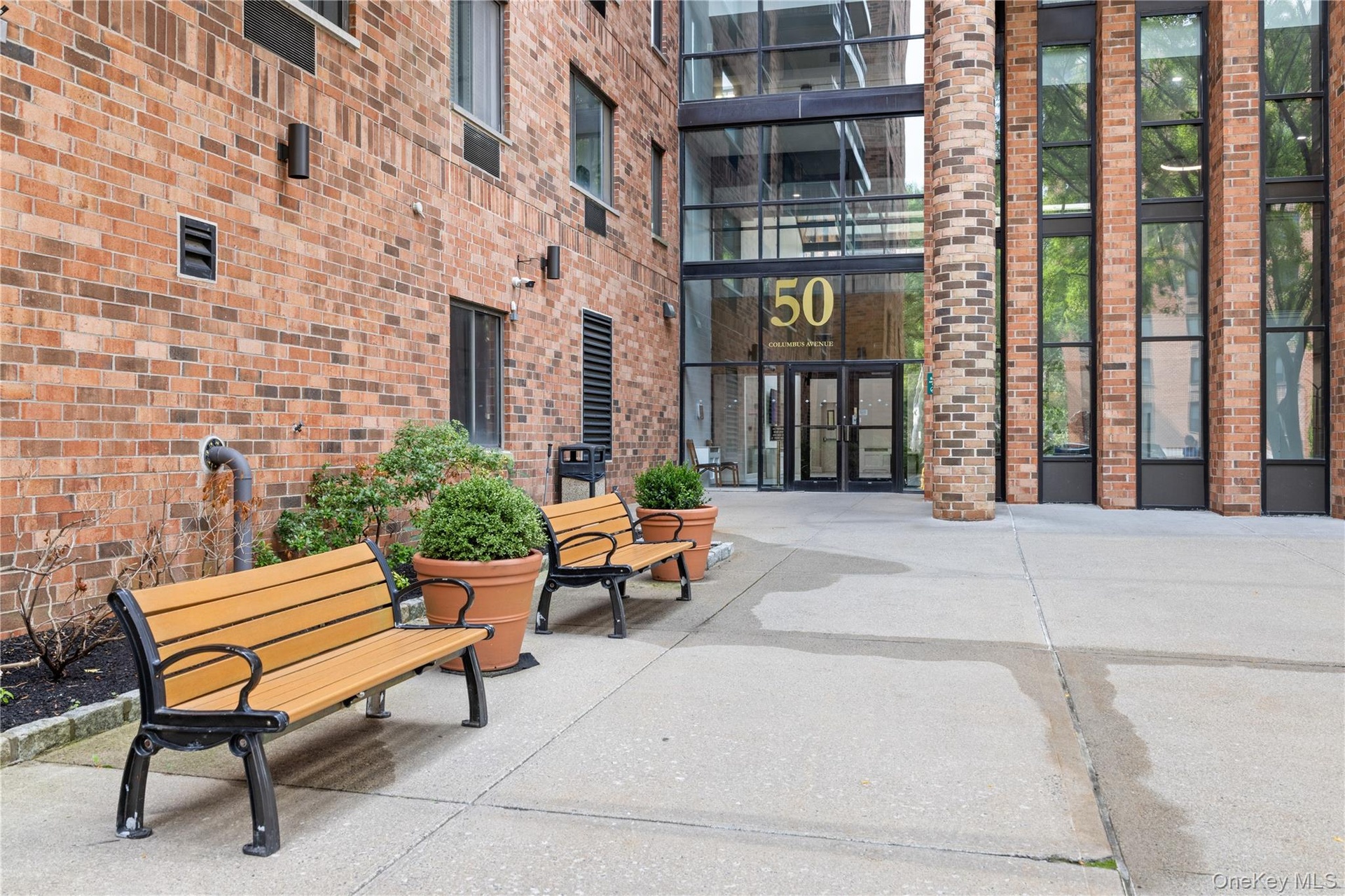 Brick exterior with a prominent glass entry, multiple large windows, and a concrete paver walkway