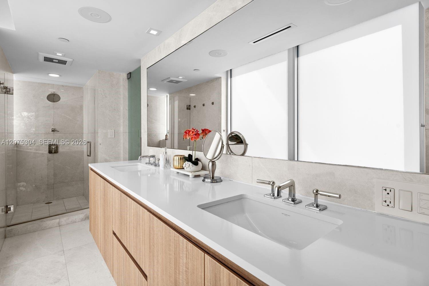 Spacious ensuite bath featuring dual sinks, oversized mirror, and glass shower — luxury meets functionality.