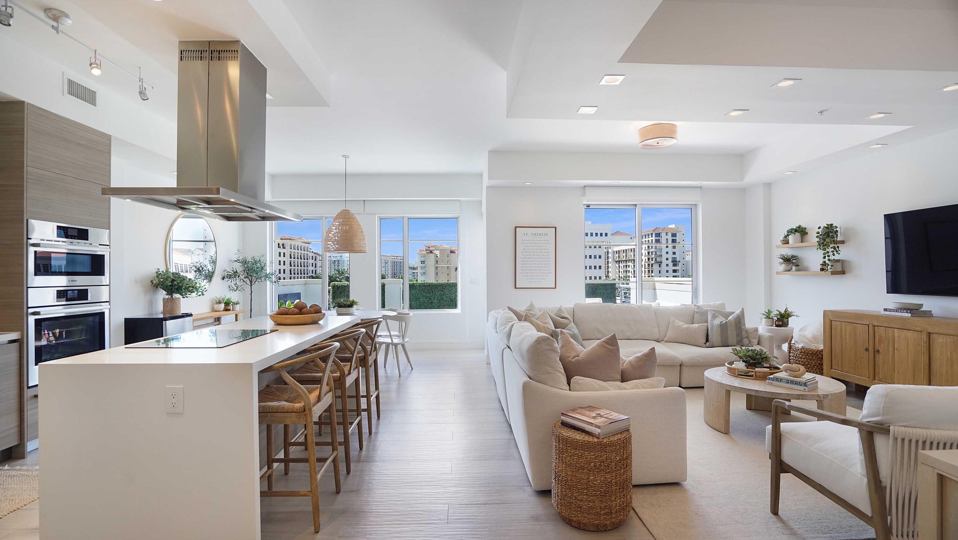 An open composition of living, dining and kitchen spaces, framed by natural light and the terrace beyond.