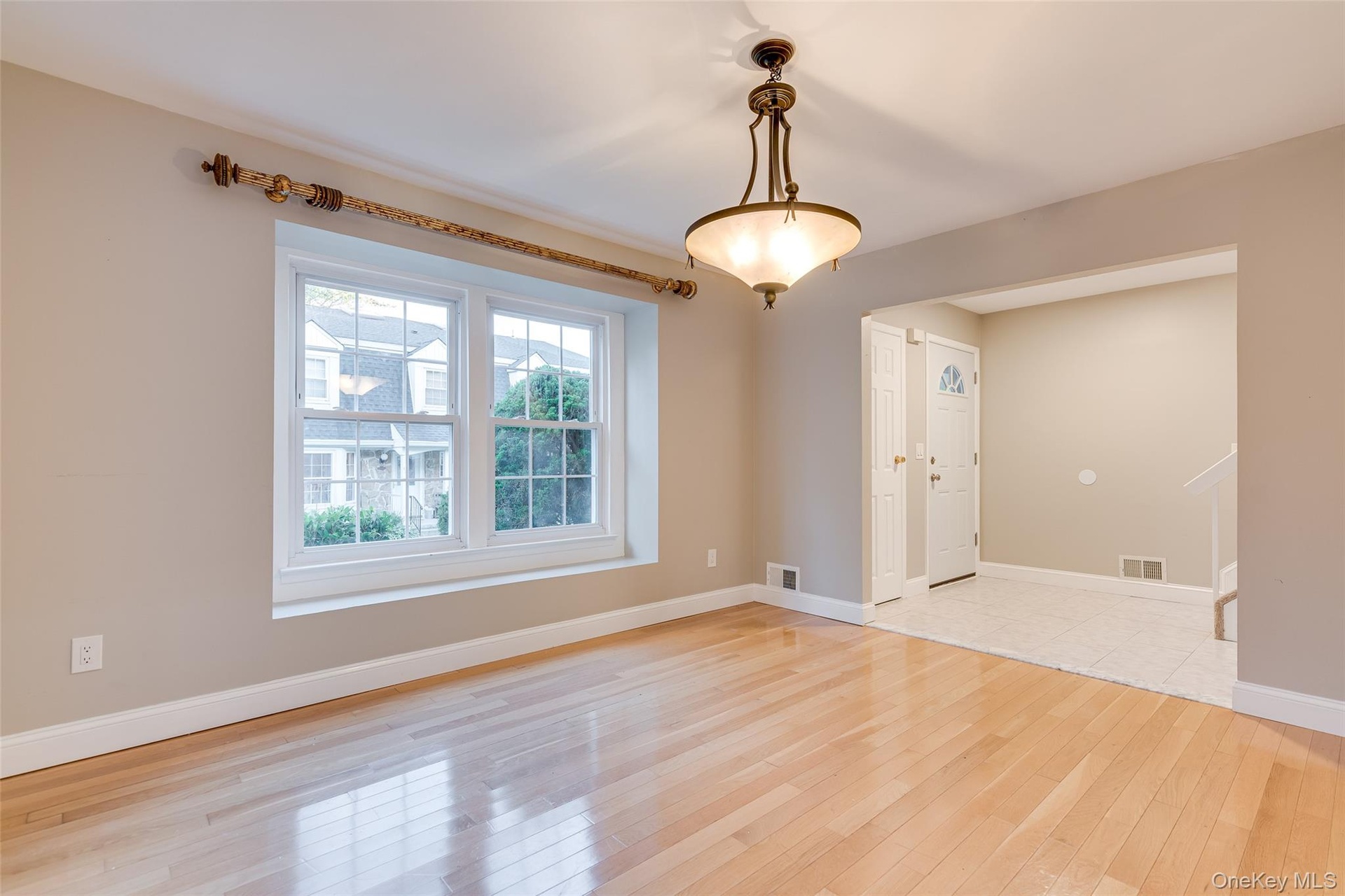 Hardwood flooring, recessed window, classic chandelier, arched entryway, and tile flooring