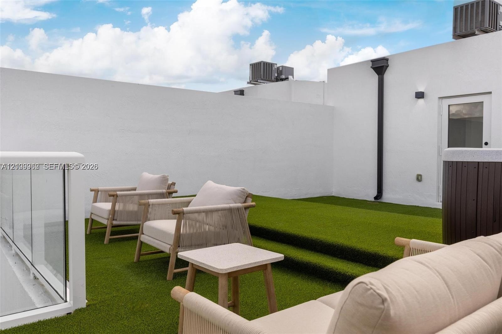 Rooftop terrace featuring tiered synthetic turf flooring, privacy perimeter walls, and a glass-panel railing