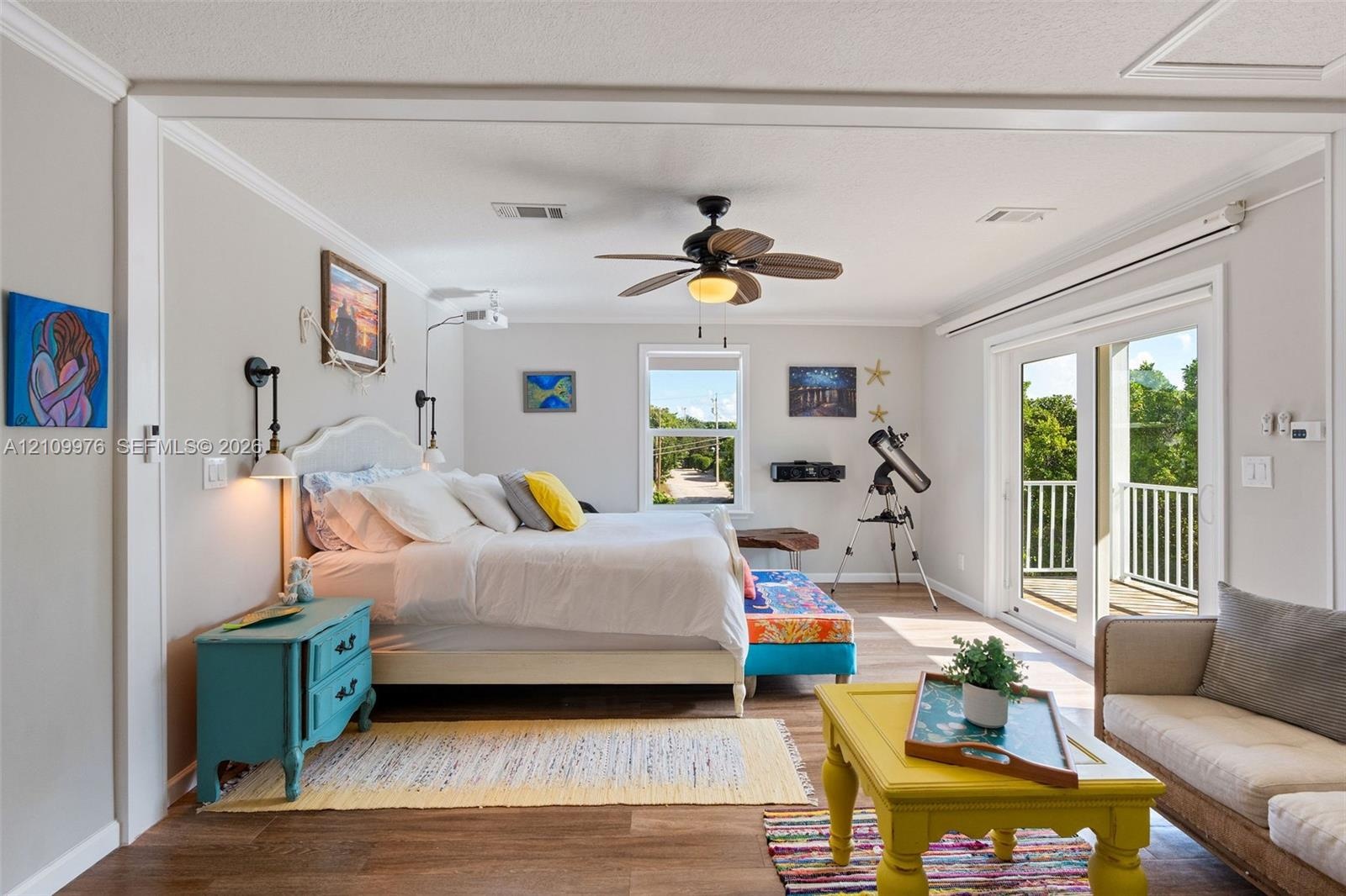 Living space featuring wood-finish flooring, a ceiling fan with integrated lighting, wall-mounted light fixtures, and glass sliding doors providing ac