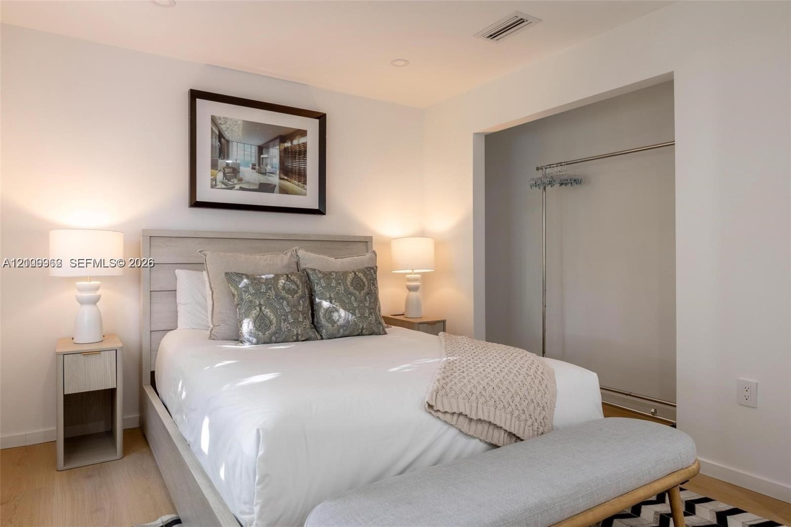 Room featuring recessed lighting, wood-finish flooring, and an open reach-in closet with an integrated metal hanging rod