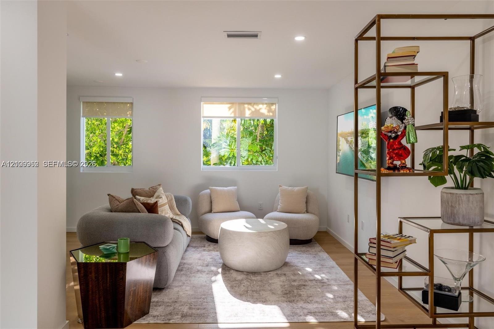 Living area featuring recessed lighting, dual windows with integrated shades, and wood-finish flooring