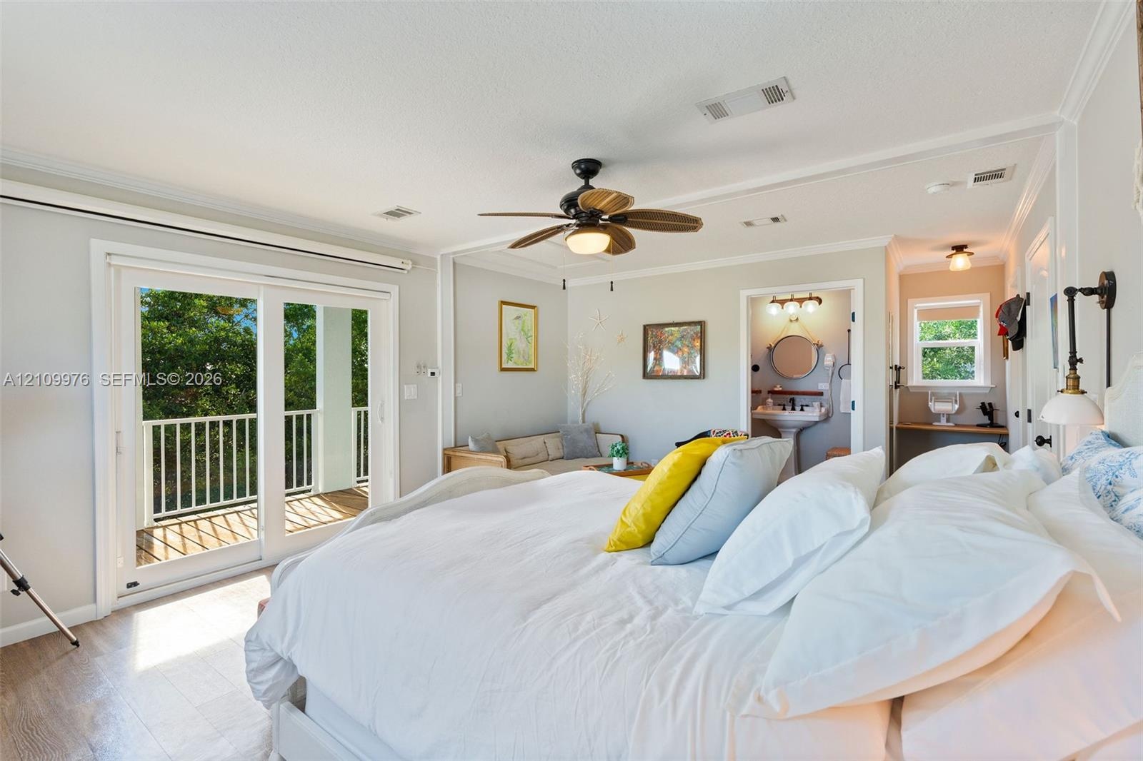 Room featuring wood-finish flooring, a ceiling fan with integrated lighting, glass sliding doors opening to an exterior balcony, crown molding, and an