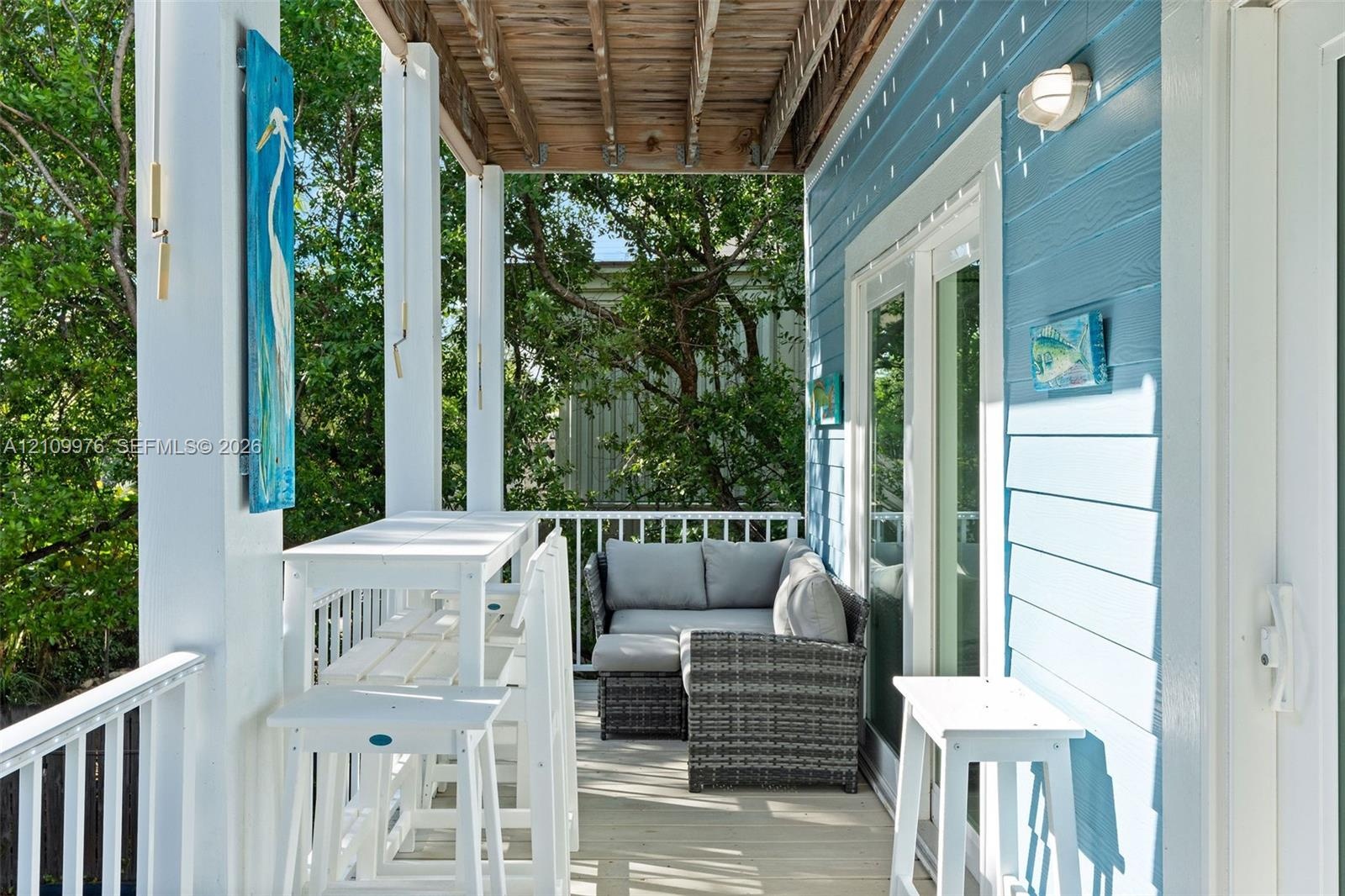 Covered porch featuring lap siding, white structural columns, wood-plank flooring, and double glass doors