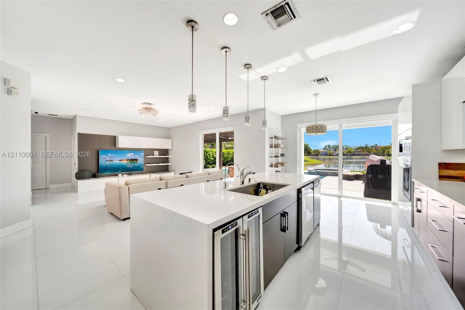Kitchen featuring a waterfall-edge stone countertop, custom cabinetry, built-in dual wine refrigeration, recessed ceiling lighting, and large sliding 
