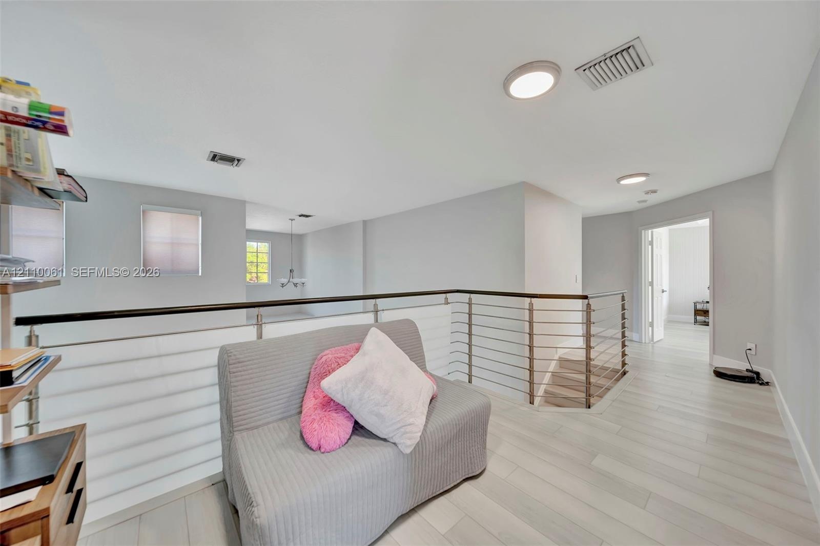 Open area featuring wood-finish flooring, metal cable railing, and recessed ceiling lighting