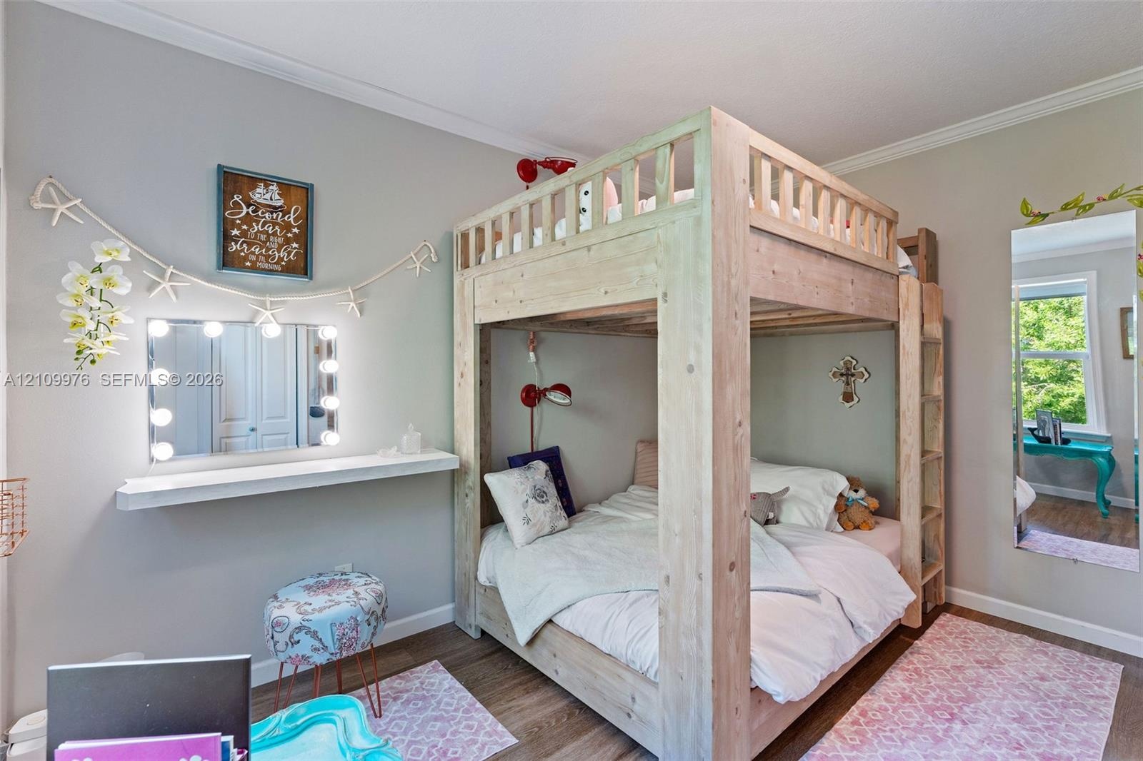 Room featuring light-toned interior paint, wood-finish flooring, and a window with natural exterior scenery