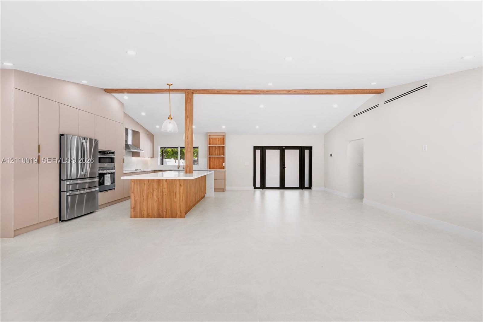 Open-concept kitchen featuring full-height flat-panel cabinetry, a wood-finish island with integrated storage, stainless steel appliances, a structura