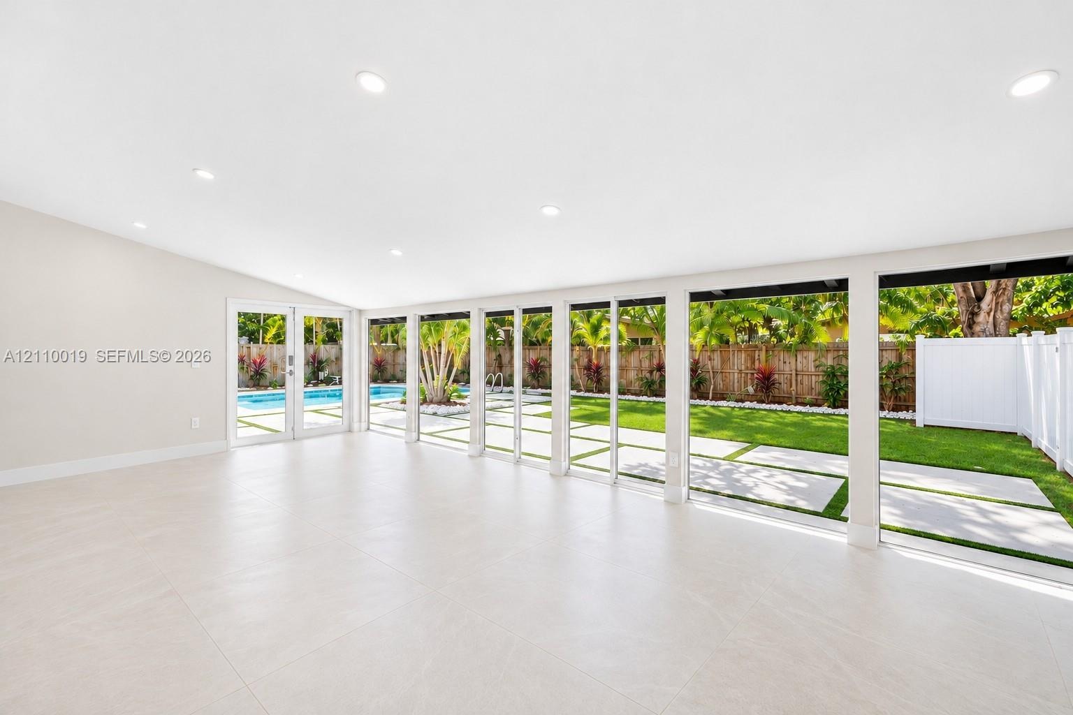 Open-concept interior featuring large-format tile flooring, recessed lighting, and expansive floor-to-ceiling glass panel doors