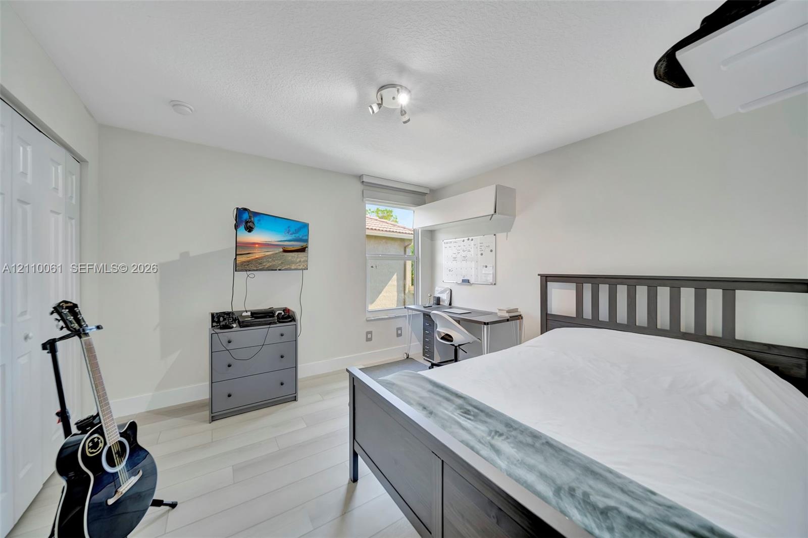 Light-toned wood-finish flooring, multi-panel closet doors, and adjustable directional track lighting