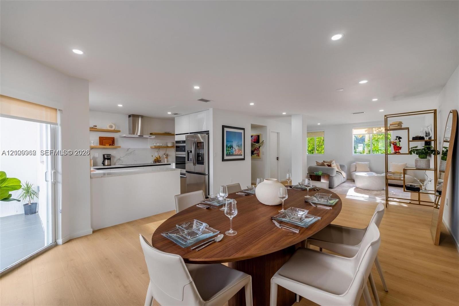 Open-concept interior featuring light wood-finish flooring, recessed lighting, a modern kitchen with built-in stainless steel appliances, floating wal