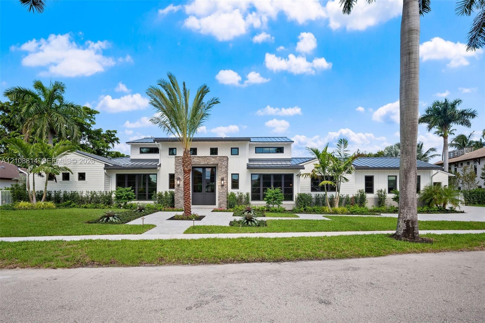 Contemporary residence featuring a clean-lined facade, multi-level roofline with metal roofing, stone veneer accent at the entryway, and expansive win
