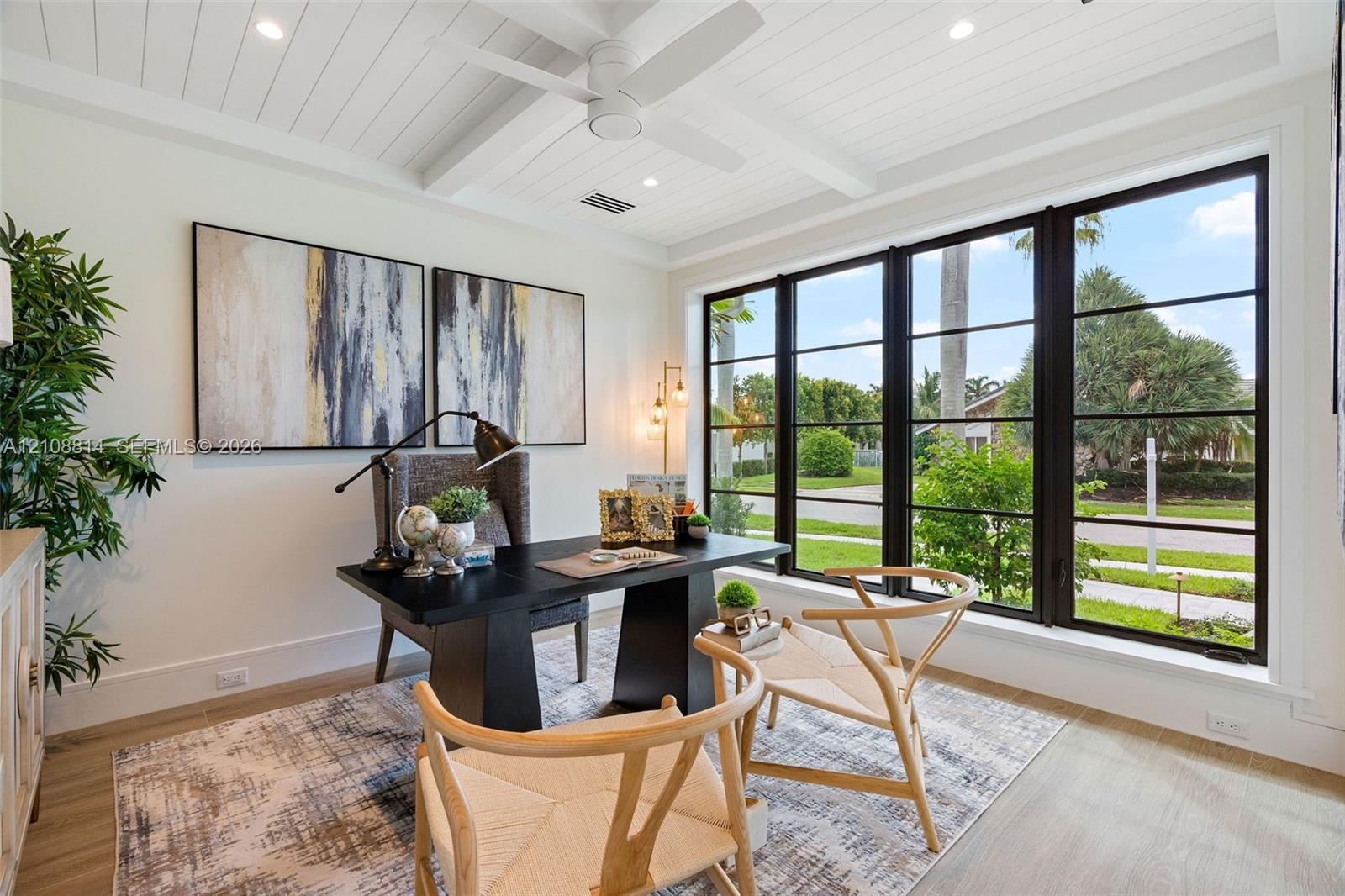 Beamed ceiling with white tongue-and-groove paneling, expansive multi-pane window wall with black frames, porcelain-finish flooring, and integrated re