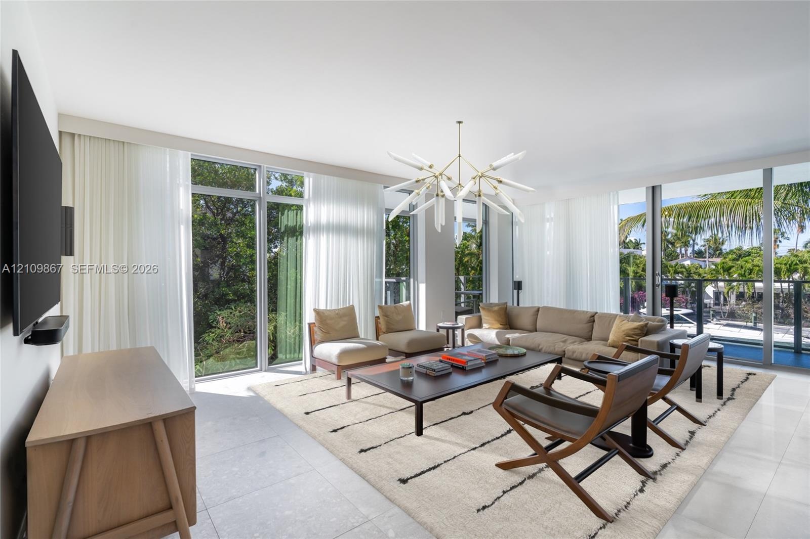 Floor-to-ceiling windows, large-format tile flooring, and a multi-arm geometric chandelier